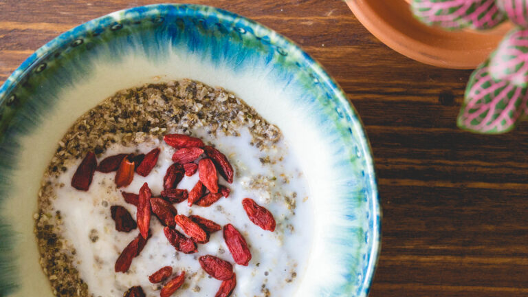 Bowl of grain-free cereal topped with coconut milk and goji berries